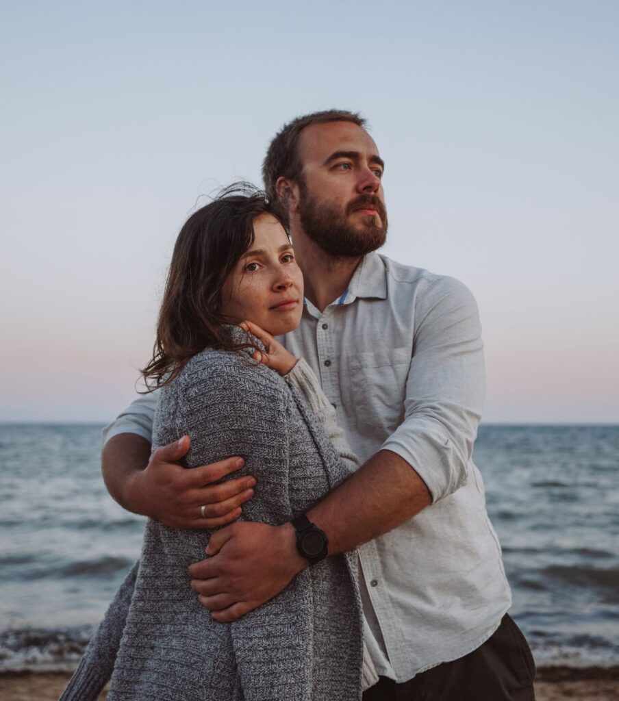 Man hugging a woman on the beach helping her with betrayal trauma. A betrayal trauma recovery expert in the United States can help couples heal from infidelity.