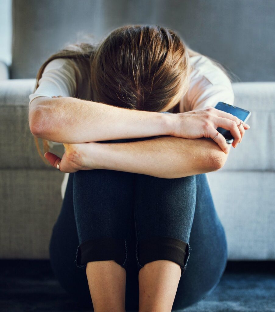 A woman sitting with her head down holding a cell phone after ending an affair. Are you struggling to end your affair? We are here to help. Schedule a free consultation with our Infidelity Recovery Program specialist to see how we can help you end your affair and rebuild your marriage again. 
