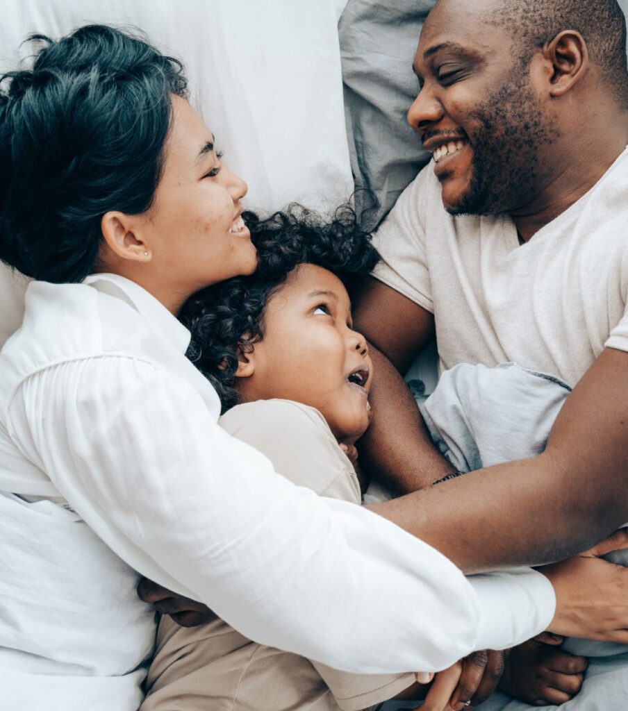 Smiling parents hugging with their daughter representing how affair recovery can help every aspect of the relationship including the children. Affair Recovery program in the United States can help spouses heal from infidelity. Schedule a consultation with Relationship Experts today.
