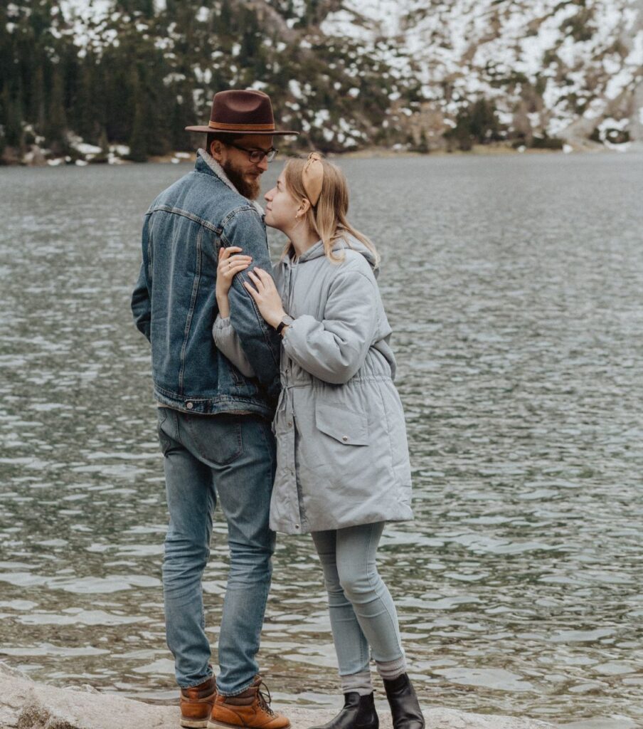 A couple standing by the lake looking at each other smiling, representing how couples can heal the pain of infidelity with an infidelity recovery program in the United States or Canada.  