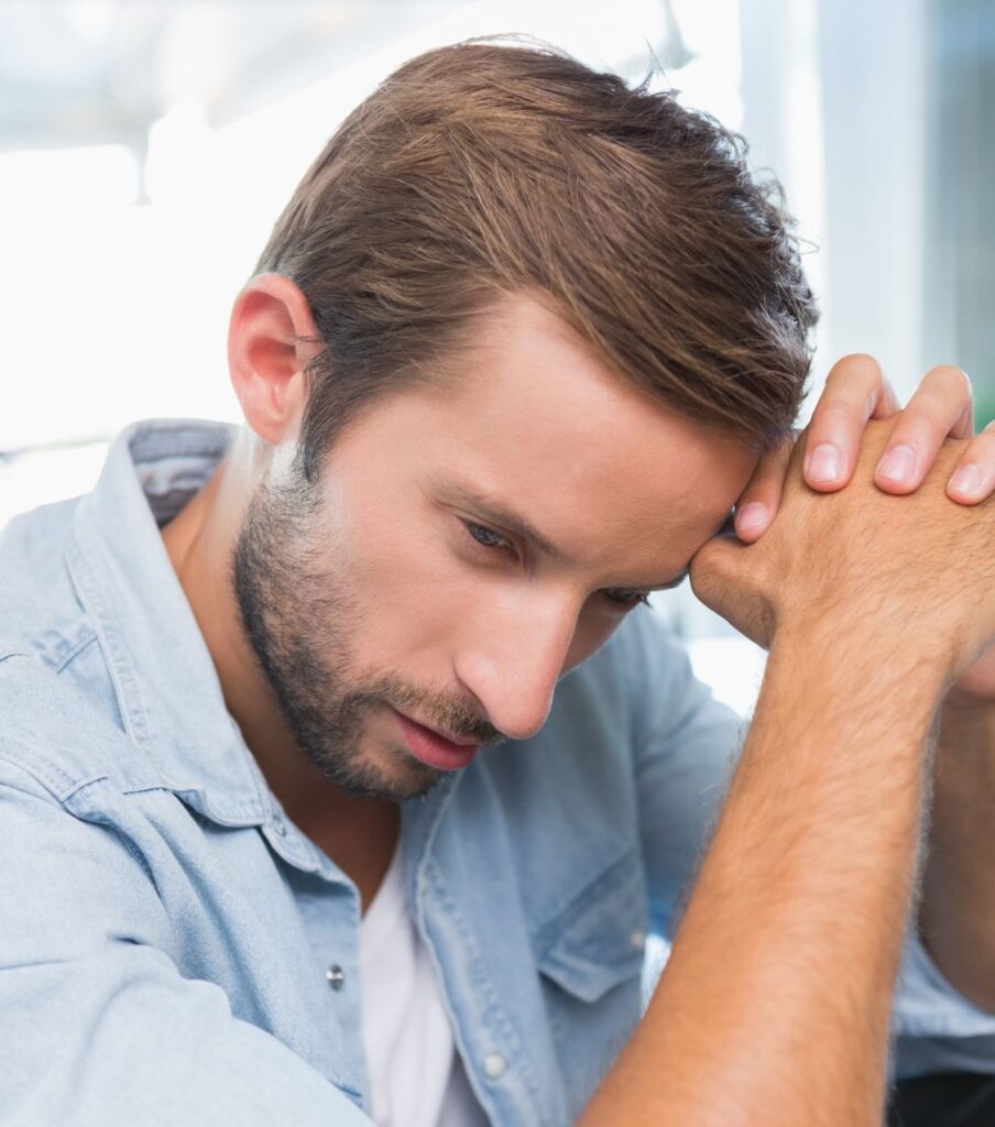 A man leaning his head on his hands, as if he is thinking how conflict avoidance can lead to infidelity. Affair recovery program in the United States can help couples survive infidelity and stop conflict avoidance. Schedule a consultation with Relationship Experts today.