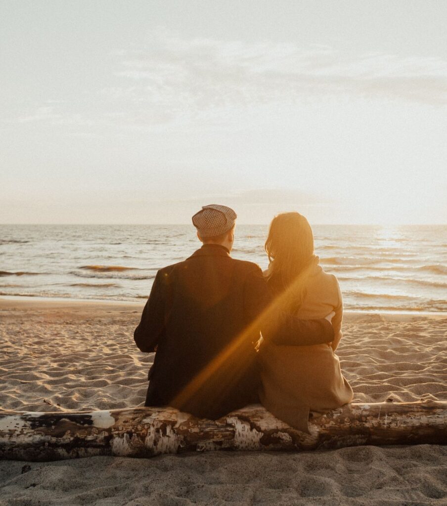 A couple sitting on the beach watching the sunset. Representing the hope you can feel if you contact our relationship experts to help you change the cycle of conflict avoidance and survive infidelity. Schedule a free consultation today!

