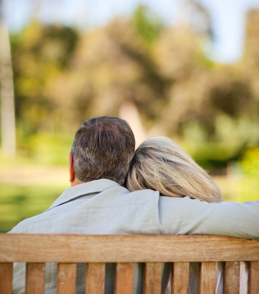 A couple sitting on a bench, leaning their heads on each other. This can represent a couple in affair recovery looking to heal from betrayal trauma and searching for solutions. If you struggle with questions about love and betrayal, an affair recovery coaching program can help. Schedule a consultation with Relationship Experts in the US, Canada, and worldwide. 
