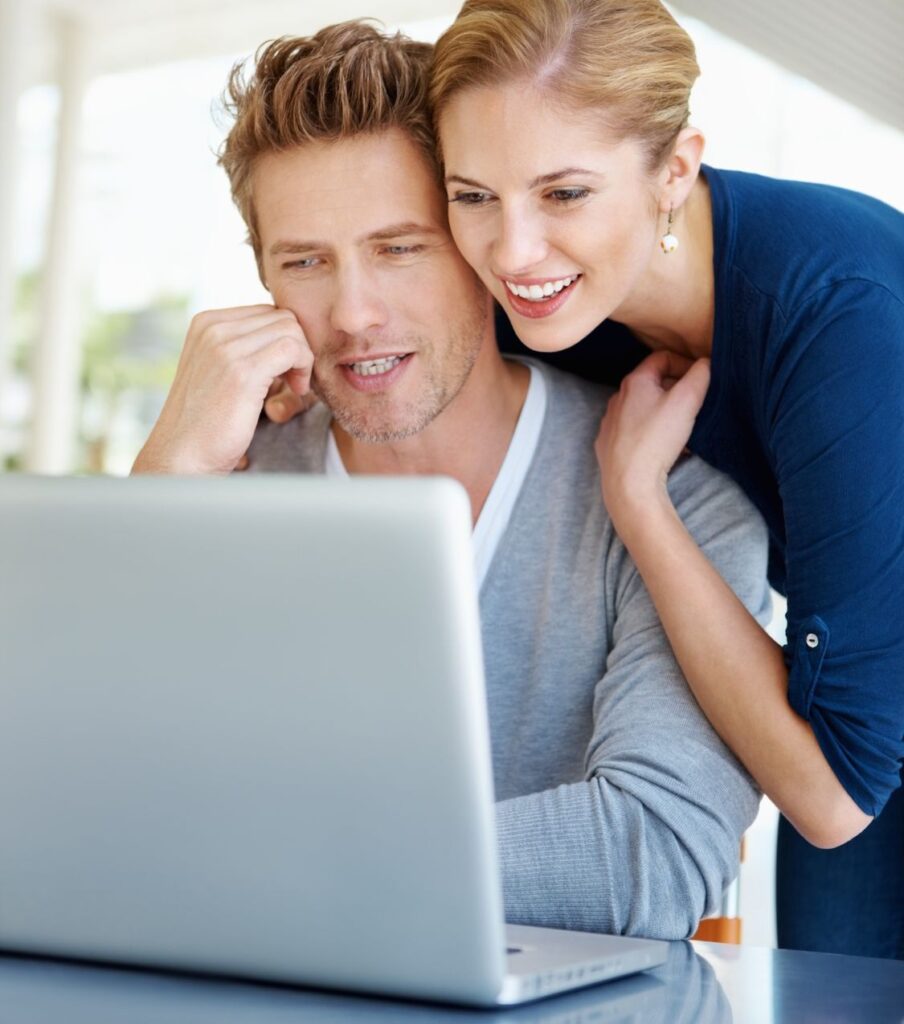 A woman and a man smiling, looking together at their computer. They look like they have found the help they need to start working on their affair recovery. Join us to start an infidelity recovery program in the USA, Canada, the UK, and anywhere else in the world
