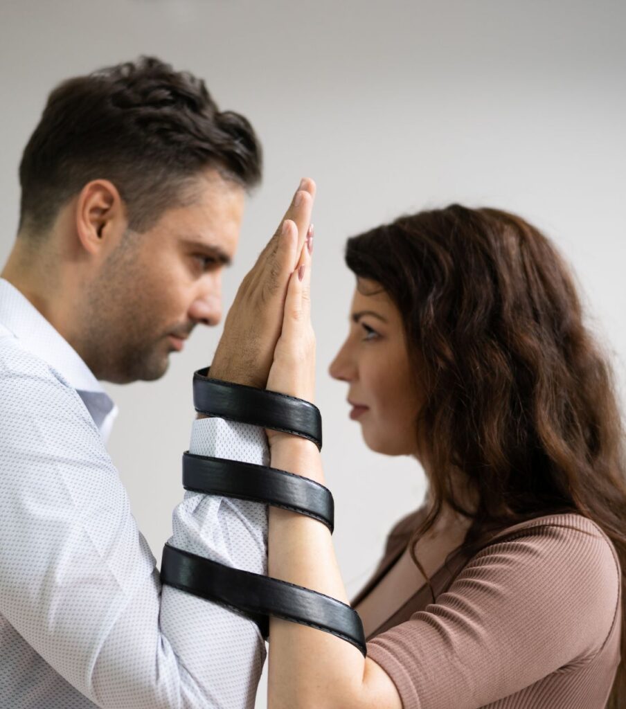 A woman and a man stand with a belt around their hands, symbolizing their commitment to staying together. Trust can be rebuilt after infidelity. Let Relationship Experts guide you on how to regain trust after cheating. Serving couples in Colorado, Virginia, New York, Florida, California, Illinois, North Carolina, United States, Canada, and globally!