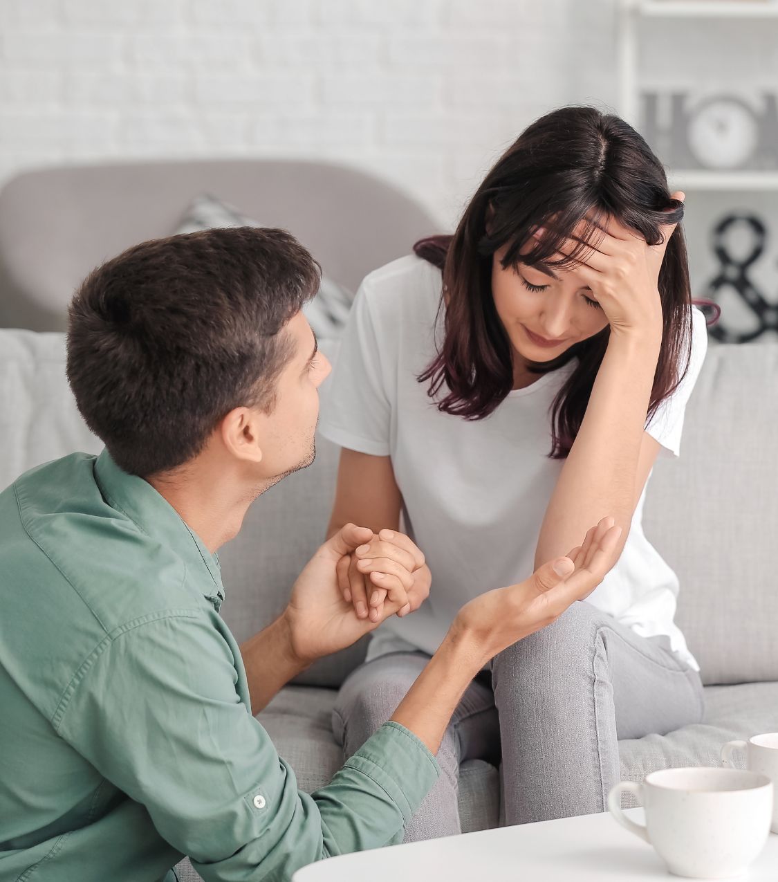 A man kneels next to his sitting wife, symbolizing reconciliation after infidelity. Relationship Experts LLC helps couples avoid common mistakes and survive infidelity, offering services in Ohio, the USA, Canada, the UK, Australia, and globally. Schedule a free consultation today!