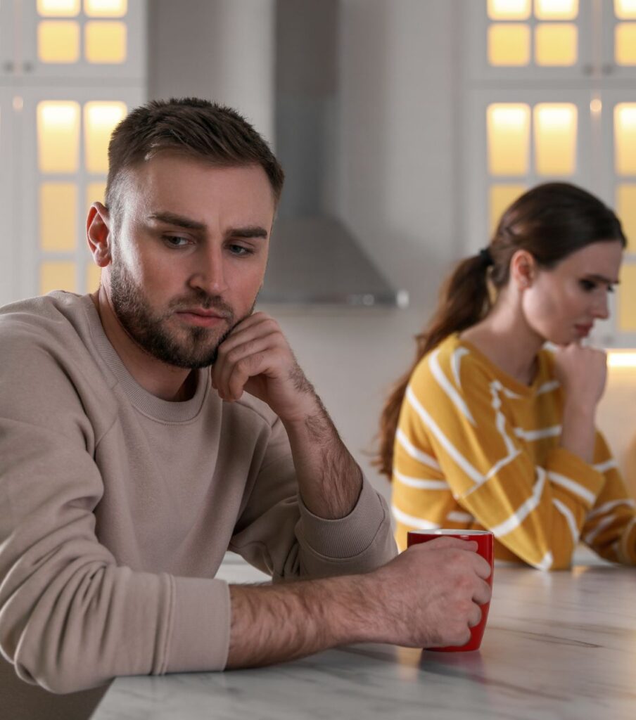 A couple sitting next to a table, looking away from each other. Relationship advice after cheating helps you see things differently. Serving couples in New York, the USA, Canada, Australia, the UK, and globally. Schedule a free consultation today!