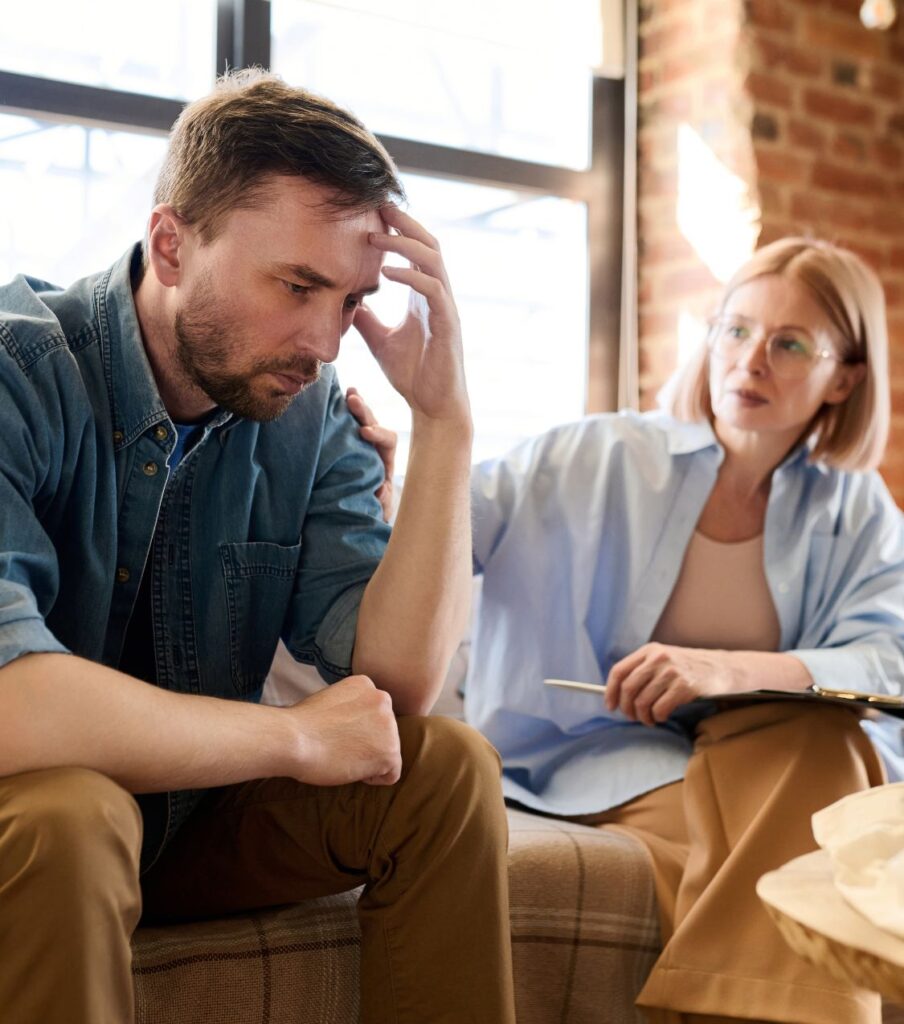 A man looking lost sits next to a therapist, symbolizing an unfaithful partner that struggles to fully express remorse. Rebuilding trust without remorse with expert help in Colorado, the USA, Australia, Canada, the UK, and globally. Contact us for a free consultation.

