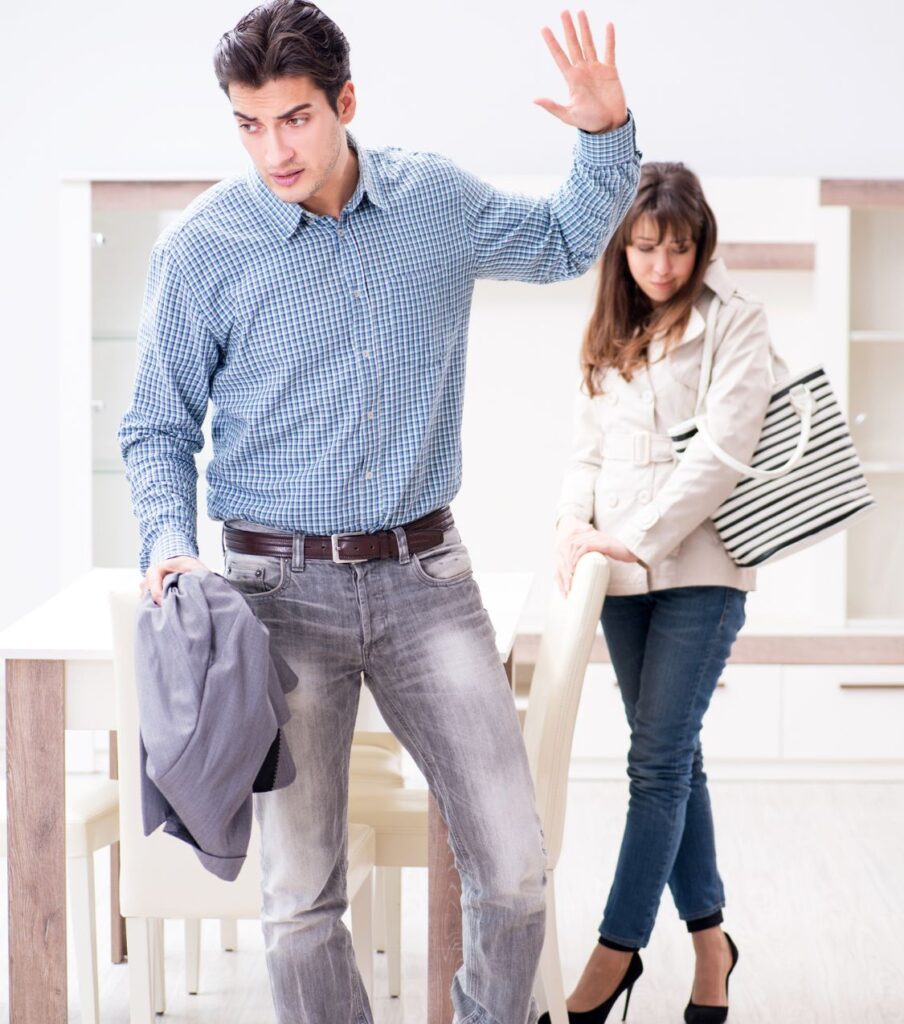 A man raises his hand while walking away from a woman, symbolizing anger and irritability—signs of Infidelity Trauma. Get expert help to rebuild your relationships in the USA and globally.