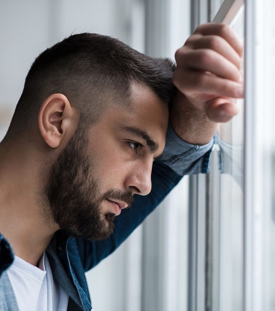 A man leans on his forehead, feeling unlovable after betrayal—a common sign of Infidelity Trauma. Schedule a free consultation to rebuild healthy relationships in the USA and globally.