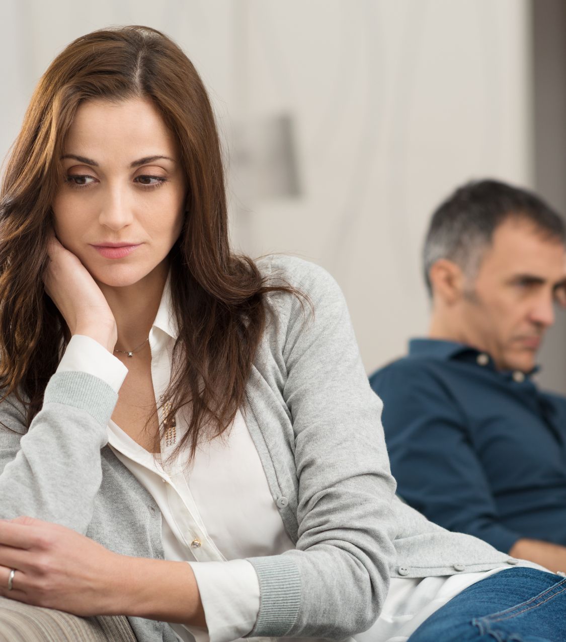 A woman sits with her back to a man, representing mistrust after an affair. Post Traumatic Infidelity Syndrome is real and needs attention. Seek help from relationship experts in the USA and globally.