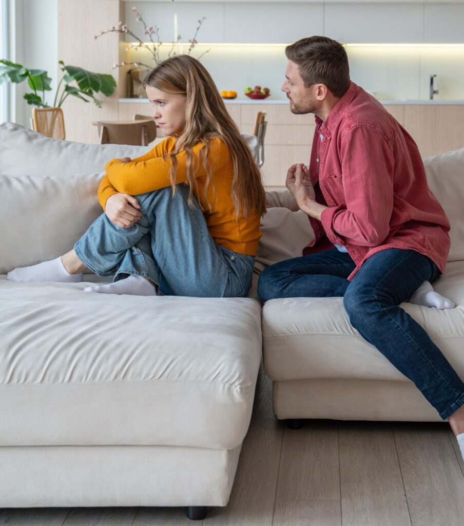 A man sitting behind a woman, trying to talk to her, symbolizing the need for healing. An infidelity recovery program can help couples rebuild after infidelity in the U.S. and worldwide.