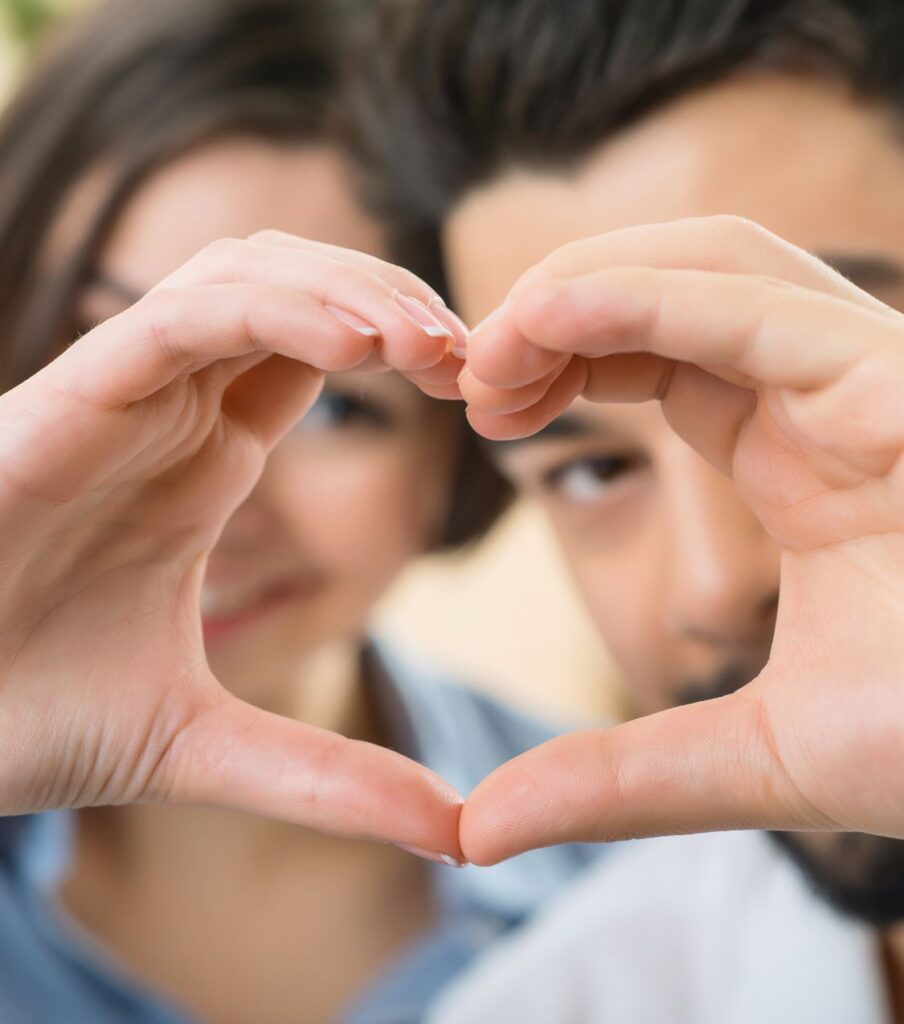 A couple forming a heart shape with their hands. Discover how to show remorse for cheating to rebuild trust and strengthen relationships in the USA and globally.