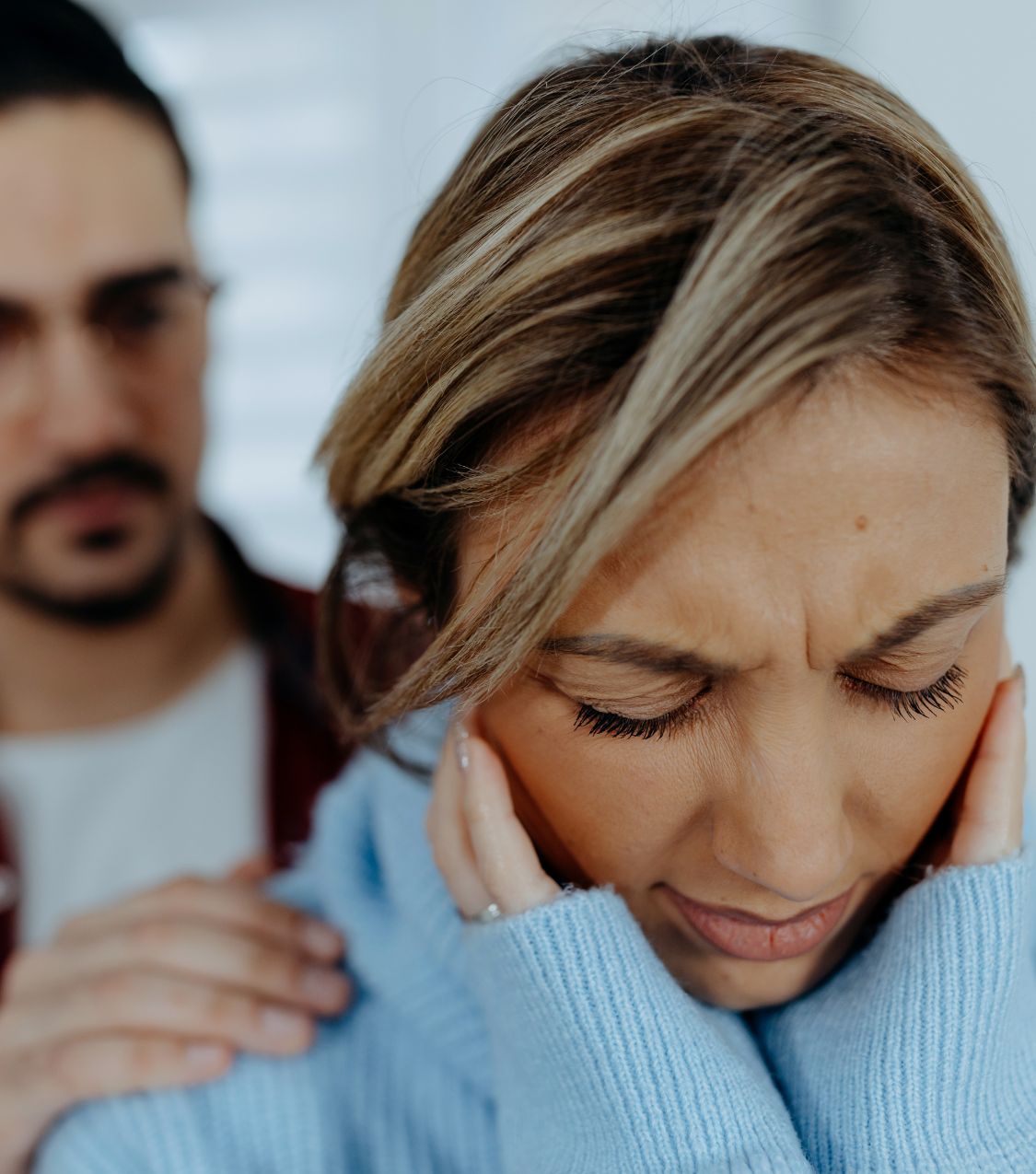 A man with his hands on a woman's shoulders, her eyes closed, reflecting the emotional weight of infidelity. Infidelity Recovery Program offers support to heal and rebuild relationships in the USA, Canada and worldwide.