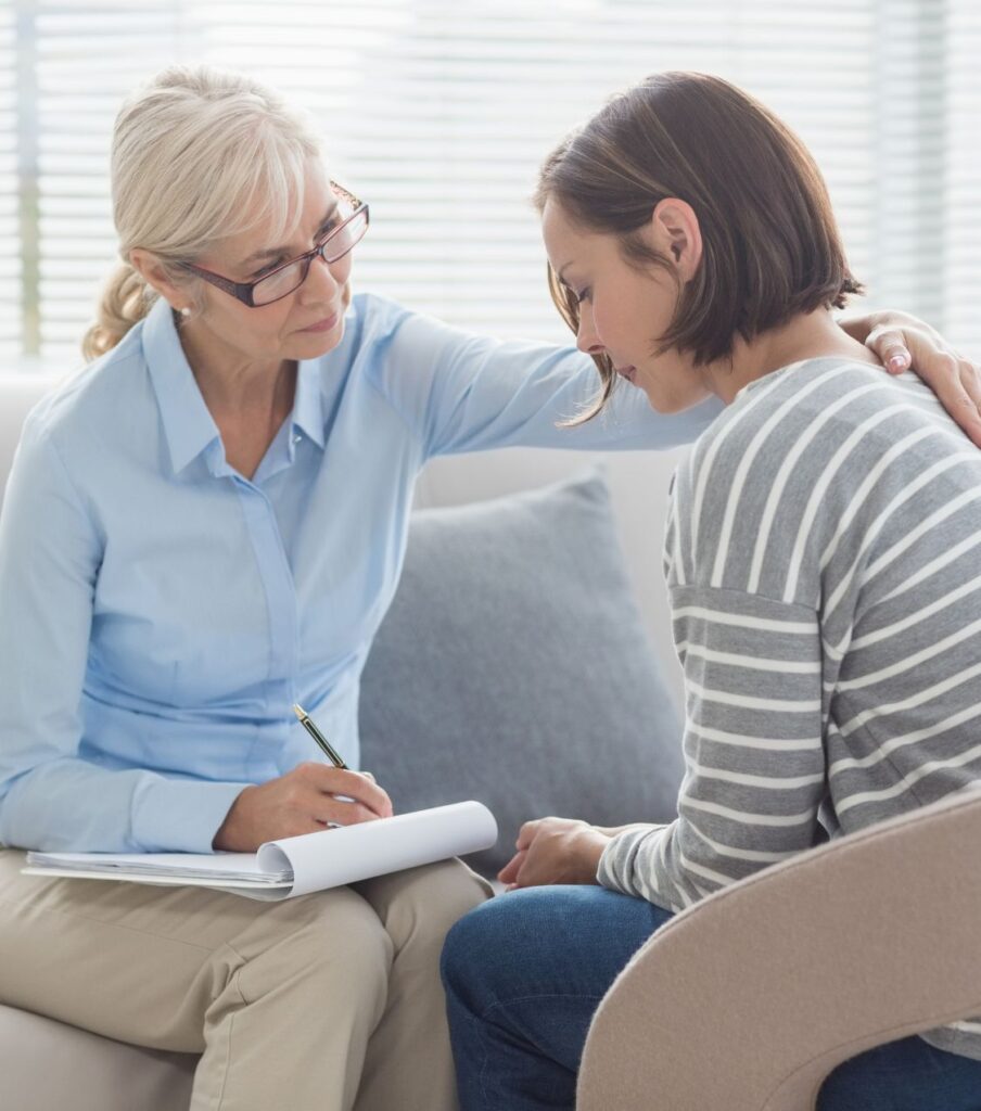 A therapist places a hand on a woman’s shoulder, symbolizing support. Specialized guidance in affair recovery can provide tools for healing after infidelity in the US.






