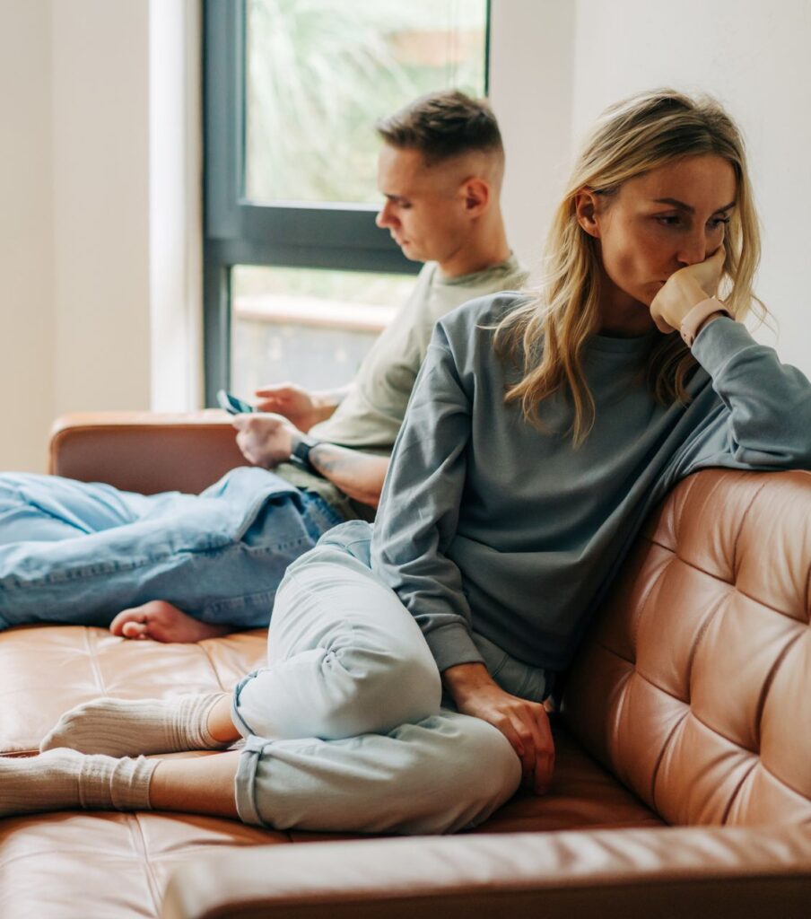 A woman sits with her back to a man, head in hand, symbolizing the belief that time alone heals after infidelity. Explore expert help for healing after infidelity in the United States and globally. 