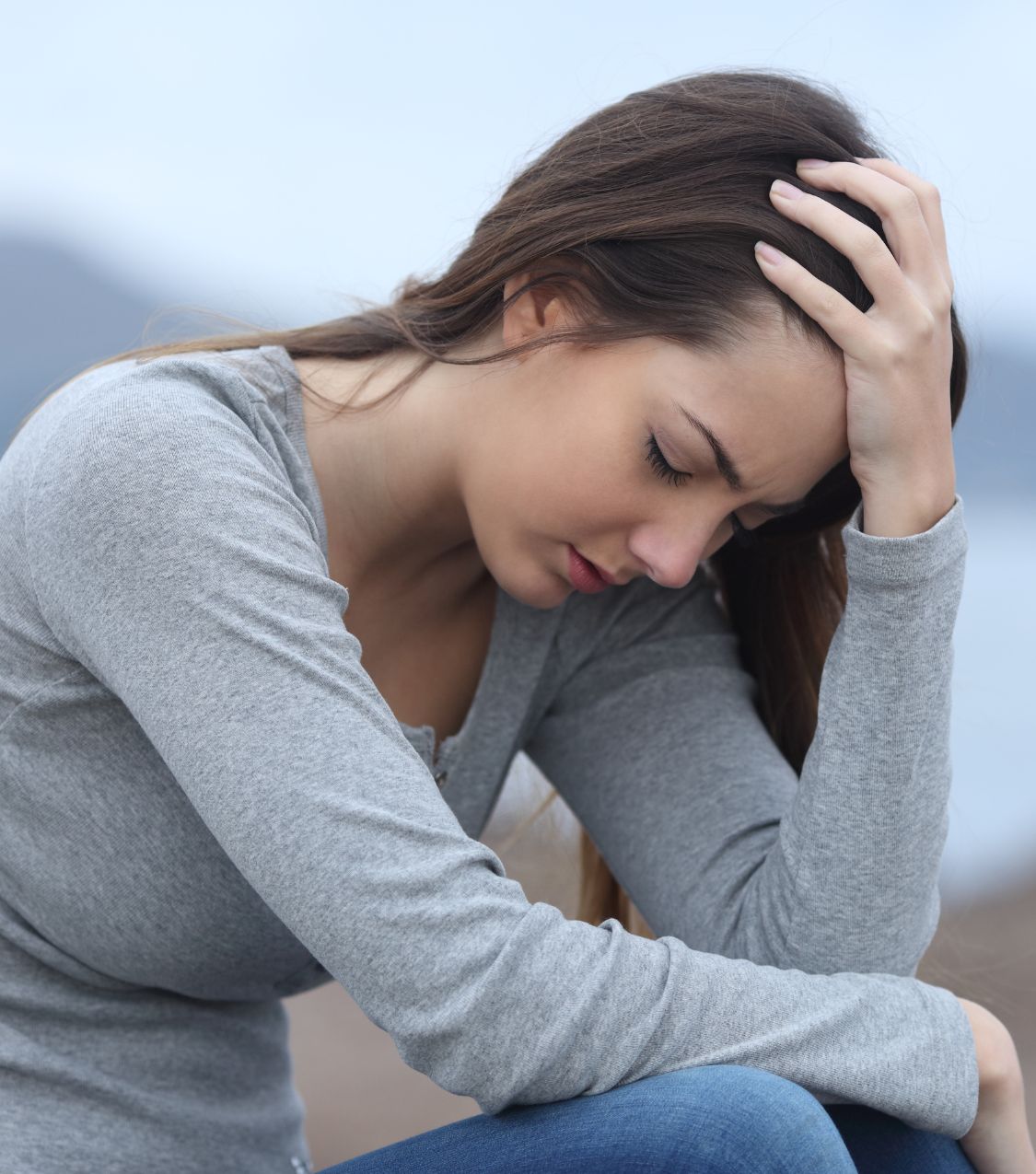 A woman leaning on her hand, reflecting on whether PTSD from infidelity is affecting her. Seek support from relationship experts in the US, Canada, and the UK to start healing.