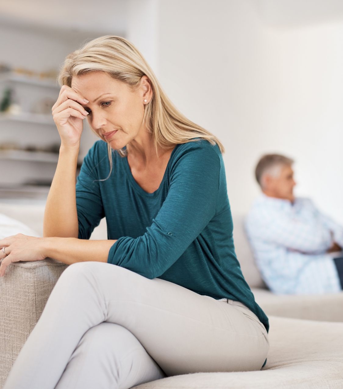 Woman sitting with her hand on her forehead, turning her back to a man, reflecting the pain of surviving infidelity. Our therapists support couples in the USA, Canada, the UK, and worldwide to survive infidelity and rebuild trust. Schedule a consultation today.