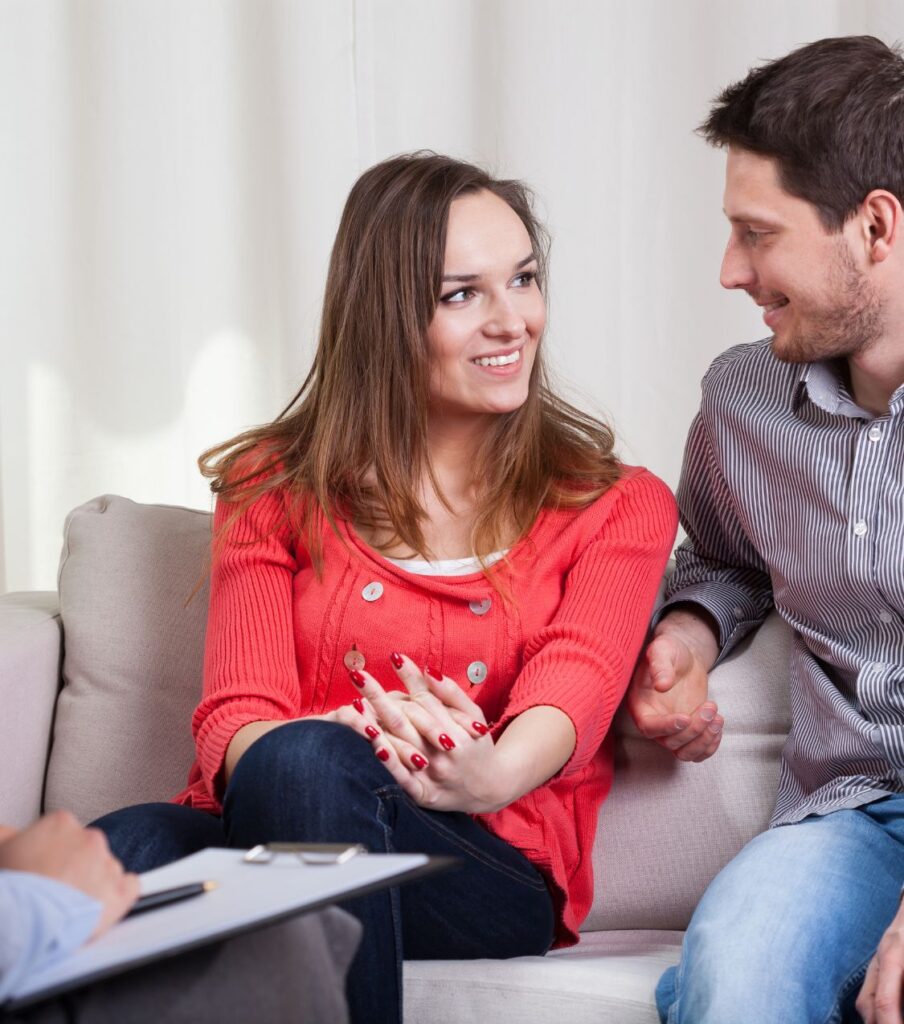 Couple smiling on a sofa next to a therapist | Understand your partner's behavior in the USA | Rebuild trust after betrayal in Canada | Sex addiction or something else in the UK Couple smiling on a sofa next to a therapist. A relationship therapist helps couples understand your partner's behavior and rebuild trust after betrayal. Serving couples in the USA, Canada, the United Kingdom, and worldwide. Schedule a call with our therapists today.