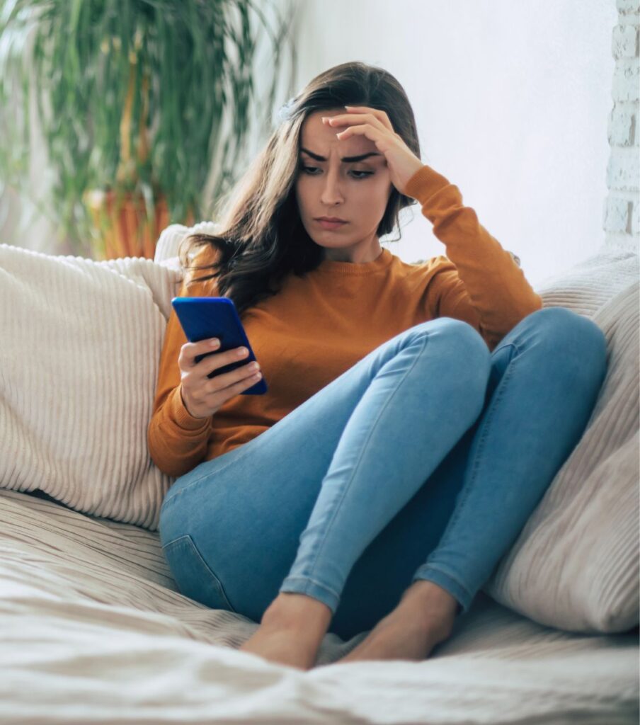A woman sitting and looking at her phone, symbolizing the search for answers after betrayal. Get support for surviving infidelity in the USA, UK, Canada, and worldwide—schedule a free consultation.
