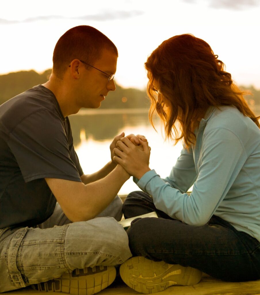 A couple sitting and holding hands, representing healing after cheating. Supporting couples surviving infidelity in the USA, Canada, the UK, and worldwide. Schedule a call today.


