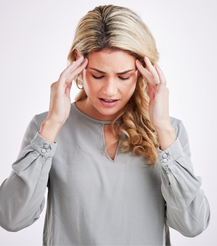 A distressed woman with hands on her forehead, symbolizing the struggle between needing details and healing after cheating; affair recovery and surviving infidelity support in the USA, Canada, the UK, and worldwide.
