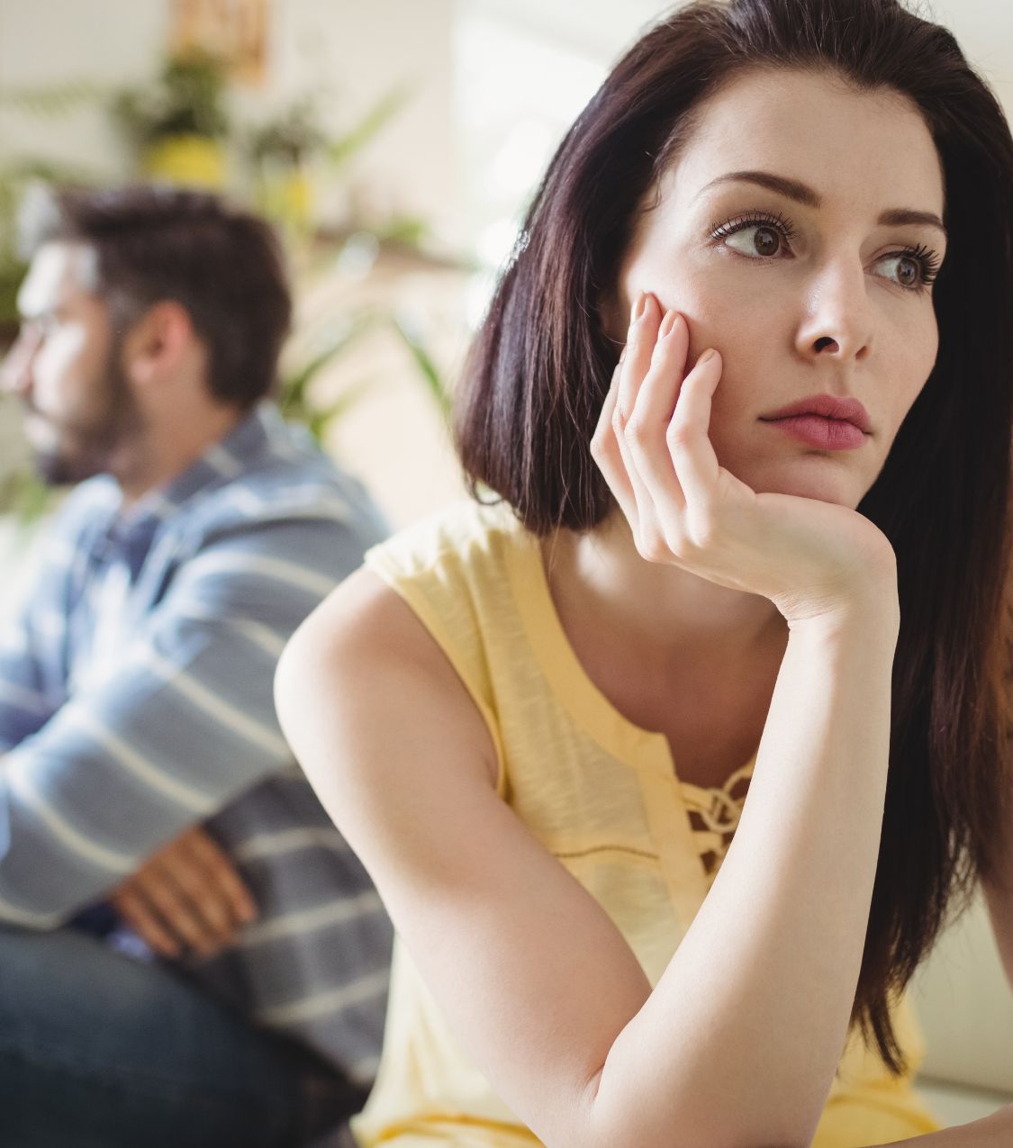 Woman looking aside while a man behind her looks the other way. Learn how to heal after betrayal and explore infidelity recovery without staying. Speak with an expert in the USA, Canada, the UK, and globally. Schedule a free consultation today.