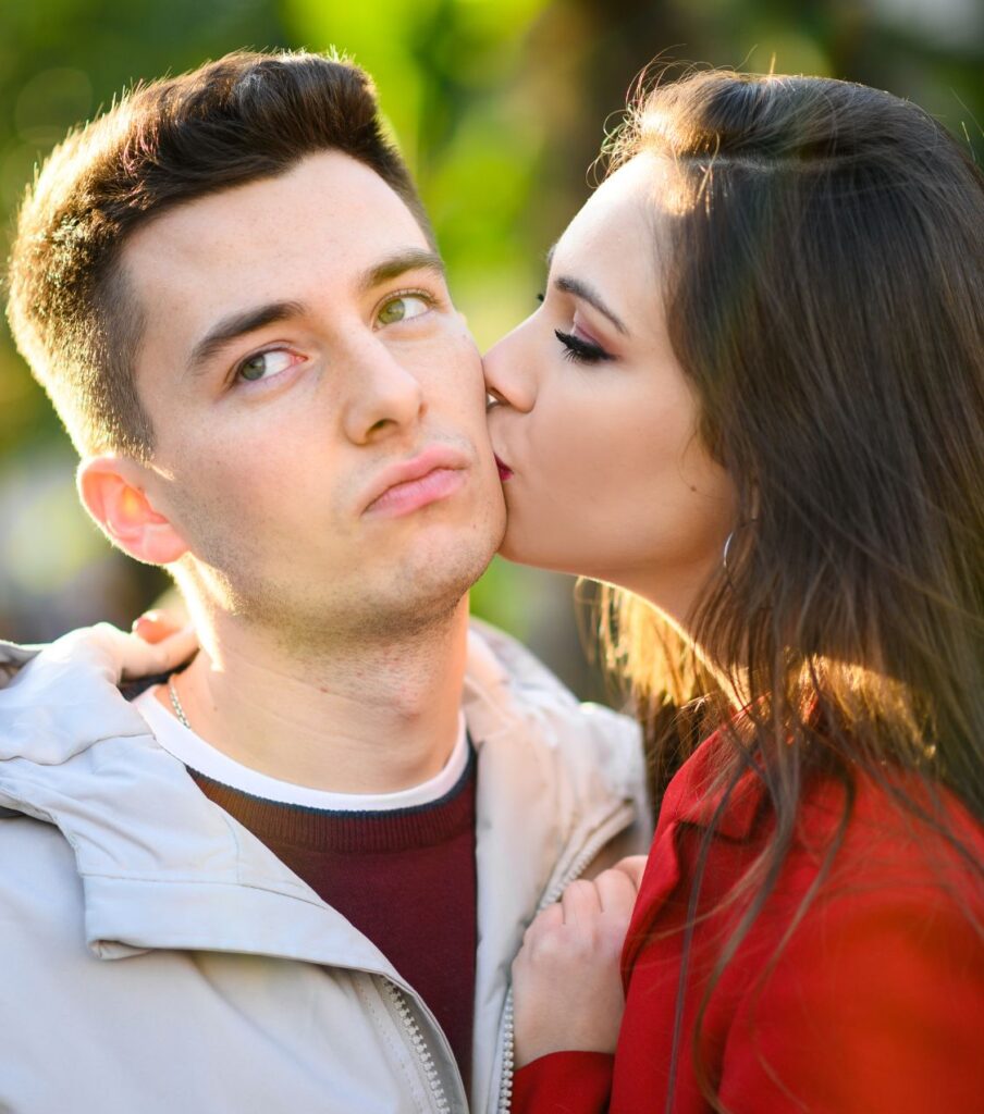 A woman kisses a man. Forgiveness after betrayal and rebuilding trust are possible with guidance. Therapists in the USA, Canada, the UK, and worldwide can help. Schedule a call with us to learn more.