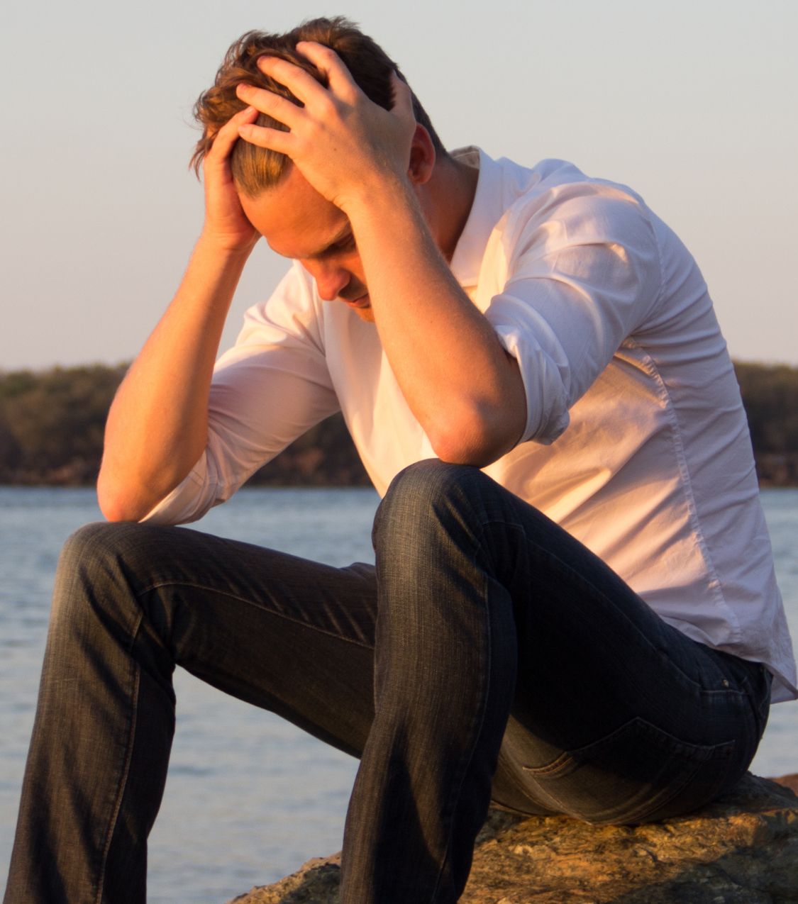 A man sitting with his head in his hands, struggling after infidelity. Relationship experts explain the three stages of affair recovery in the USA, Canada, the UK, and globally. Schedule a free consultation today.