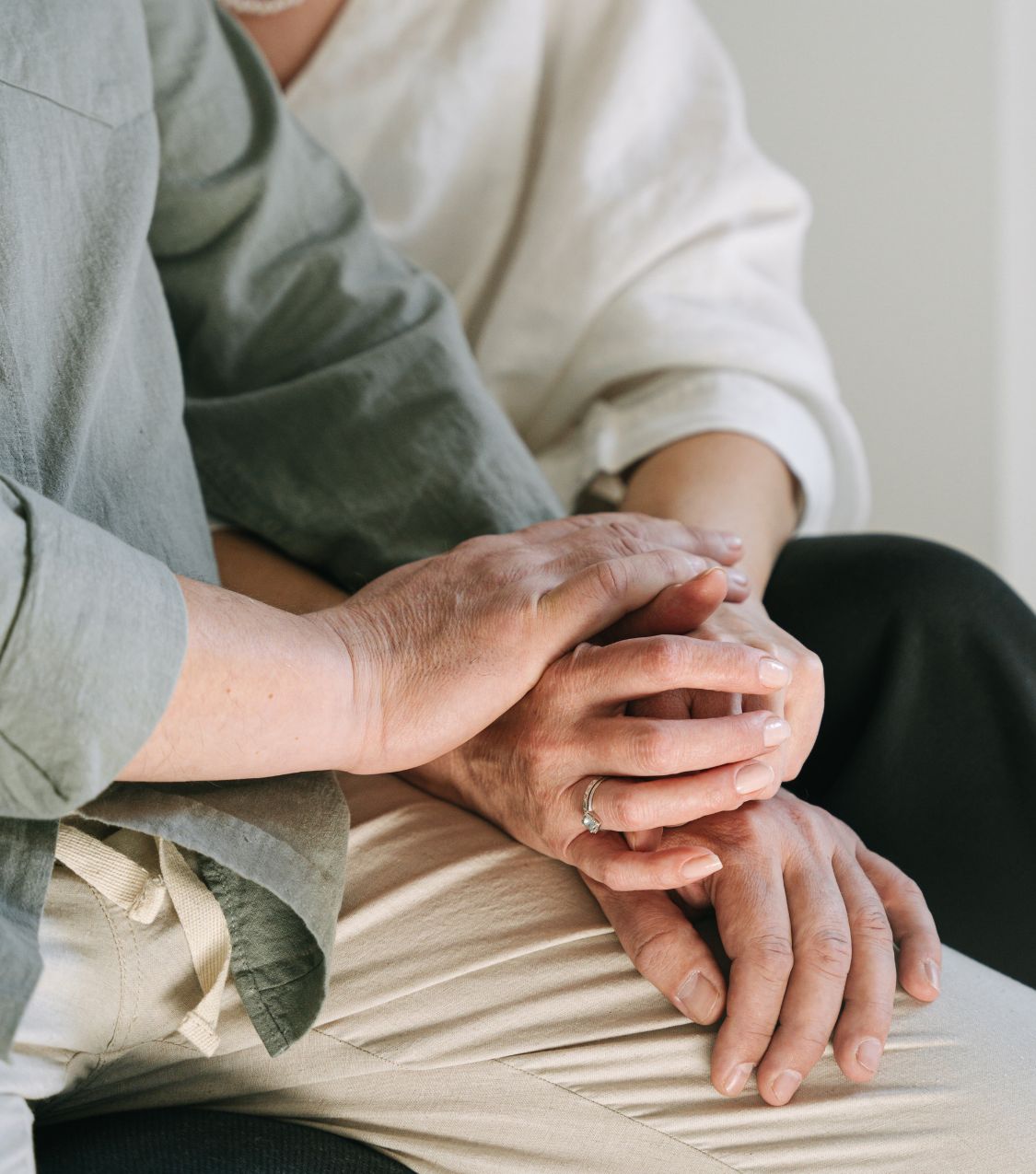 A close-up of two people gently holding hands, conveying the emotional weight and hope for healing after a partner had a same-sex affair and questions about sexuality arise. Licensed couples therapists specializing in same-sex betrayal recovery support clients in the USA, Canada, and Australia. If your partner had a same-sex affair, reach out to our team today.