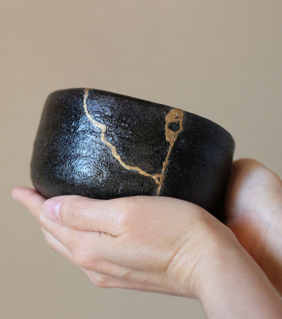Two hands gently cradle a black ceramic bowl repaired with visible gold seams where it once cracked, a kintsugi-style symbol of repair. Can a straight marriage survive a same-sex affair? For couples exploring why would a straight man have an affair with a man, or navigating sexual fluidity in a straight marriage. Healing is possible - for couples in Australia, Dubai, and the USA. Schedule your free consultation to start rebuilding trust.